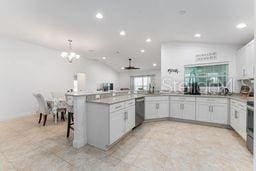 kitchen featuring stainless steel dishwasher, white cabinets, kitchen peninsula, pendant lighting, and a breakfast bar area