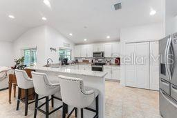 kitchen featuring vaulted ceiling, white cabinets, kitchen peninsula, a breakfast bar, and stainless steel appliances