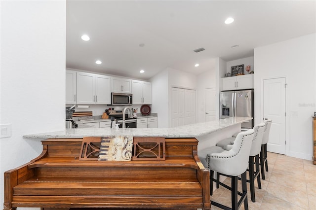 kitchen featuring white cabinets, stainless steel appliances, kitchen peninsula, and a kitchen breakfast bar