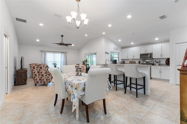 tiled dining room featuring vaulted ceiling and ceiling fan with notable chandelier