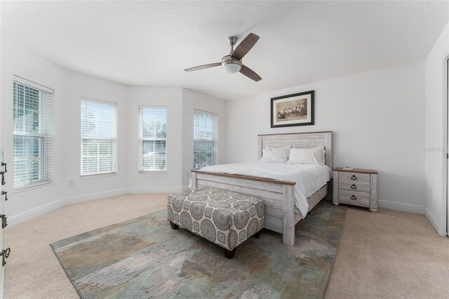 bedroom featuring ceiling fan, light colored carpet, and multiple windows