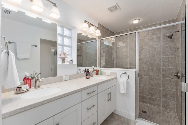 bathroom with a textured ceiling, an enclosed shower, vanity, and tile patterned flooring