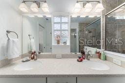 bathroom featuring a shower with shower door and vanity