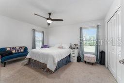 bedroom with light carpet, multiple windows, and ceiling fan