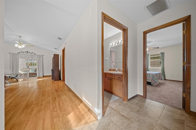 hallway with light tile patterned floors, vaulted ceiling, and sink