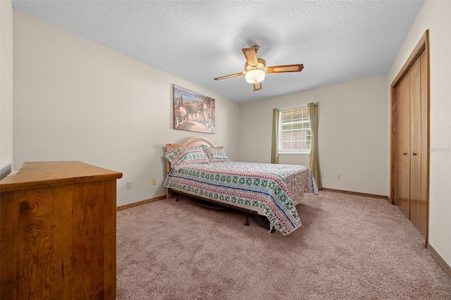 bedroom with ceiling fan, a textured ceiling, a closet, and light carpet