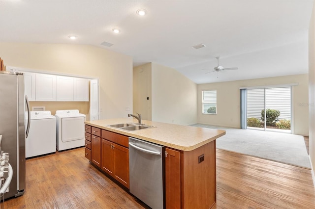 kitchen with lofted ceiling, sink, a center island with sink, appliances with stainless steel finishes, and washing machine and dryer