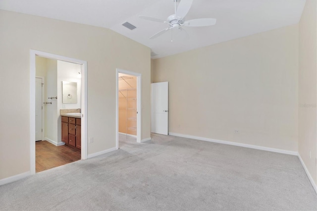 unfurnished bedroom with lofted ceiling, ensuite bath, a spacious closet, a closet, and ceiling fan