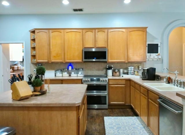 kitchen with dark wood-type flooring, sink, tasteful backsplash, a kitchen island, and stainless steel appliances