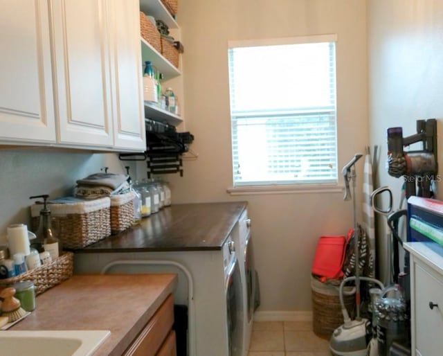 laundry area with light tile patterned flooring, cabinets, and washing machine and dryer