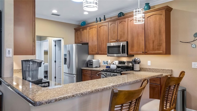 kitchen with pendant lighting, appliances with stainless steel finishes, kitchen peninsula, light stone counters, and a breakfast bar