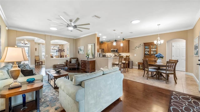 living room featuring ceiling fan with notable chandelier, dark hardwood / wood-style floors, and ornamental molding