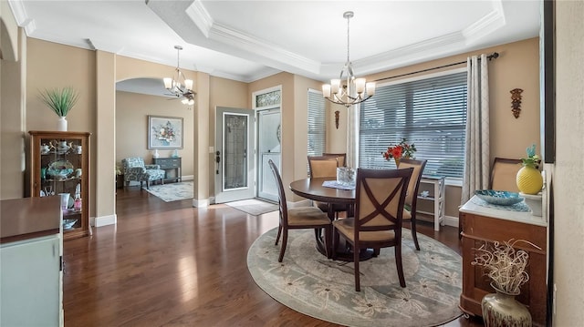 dining area featuring ornamental molding, an inviting chandelier, dark hardwood / wood-style flooring, and a raised ceiling