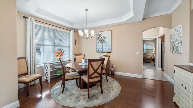 dining room featuring crown molding, dark hardwood / wood-style flooring, a raised ceiling, and a notable chandelier