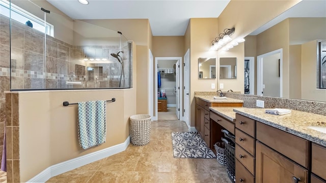 bathroom featuring tile patterned floors, tiled shower, and vanity