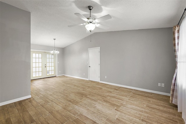 unfurnished room featuring a textured ceiling, ceiling fan with notable chandelier, vaulted ceiling, and french doors