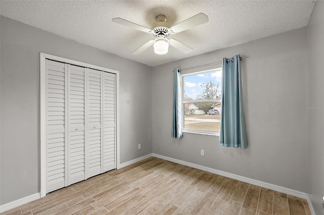 unfurnished bedroom with light hardwood / wood-style floors, a textured ceiling, a closet, and ceiling fan