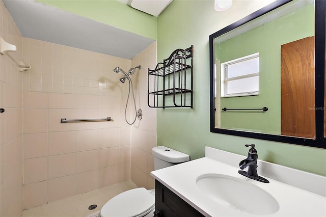 bathroom featuring toilet, vanity, and a tile shower