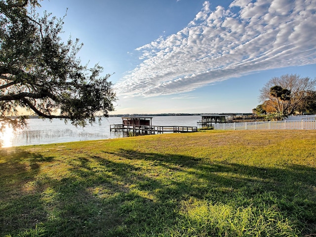 view of dock with a water view and a lawn