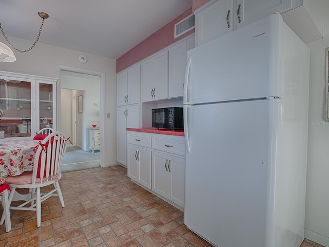 kitchen with white refrigerator, white cabinetry, and decorative light fixtures