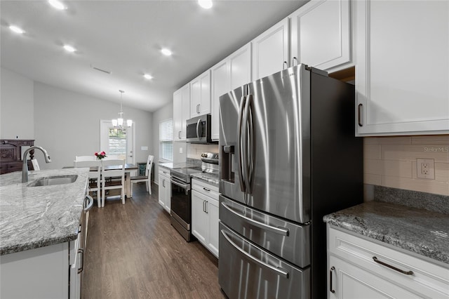 kitchen with lofted ceiling, sink, appliances with stainless steel finishes, hanging light fixtures, and white cabinets