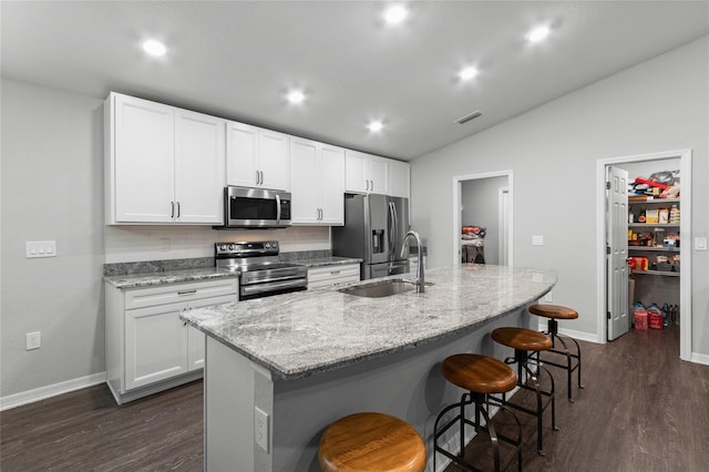 kitchen with appliances with stainless steel finishes, sink, a center island with sink, and white cabinets