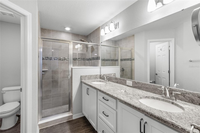 bathroom with hardwood / wood-style flooring, vanity, a textured ceiling, toilet, and walk in shower