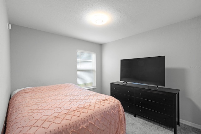 bedroom featuring light carpet and a textured ceiling