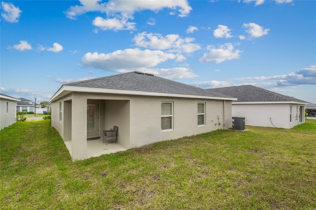 back of property with central AC, a patio area, and a lawn