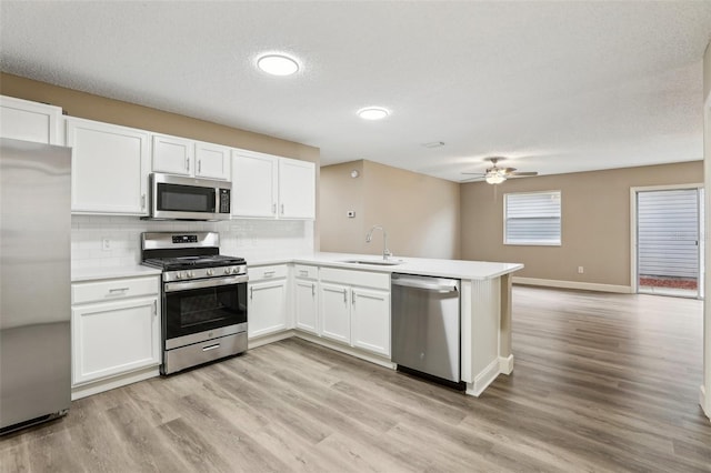 kitchen featuring sink, white cabinetry, stainless steel appliances, light hardwood / wood-style floors, and kitchen peninsula