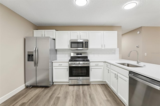 kitchen featuring sink, light hardwood / wood-style flooring, stainless steel appliances, decorative backsplash, and white cabinets