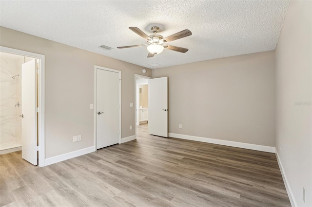 unfurnished bedroom featuring ceiling fan, a textured ceiling, light wood-type flooring, and ensuite bath