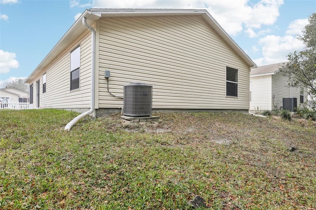 view of side of home featuring a lawn and central air condition unit