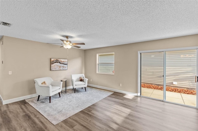 17461 SE 93rd Retford Ter, The Villages, FL 32162 - living area featuring wood finished floors, visible vents, a ceiling fan, baseboards, and a textured ceiling