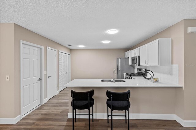 17461 SE 93rd Retford Ter, The Villages, FL 32162 - kitchen featuring a sink, a breakfast bar, dark wood finished floors, a peninsula, and appliances with stainless steel finishes