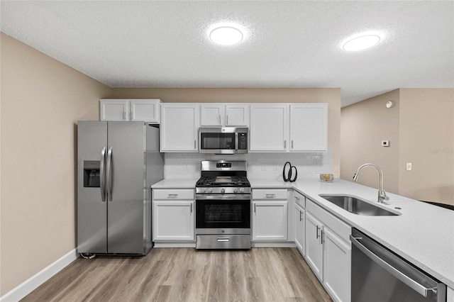 17461 SE 93rd Retford Ter, The Villages, FL 32162 - kitchen featuring white cabinets, light wood finished floors, stainless steel appliances, a sink, and a textured ceiling