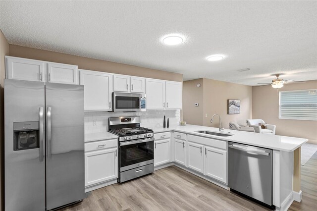 17461 SE 93rd Retford Ter, The Villages, FL 32162 - kitchen with a peninsula, a sink, white cabinetry, light countertops, and appliances with stainless steel finishes