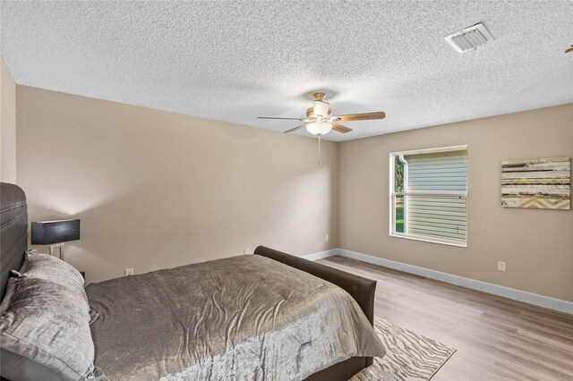 17461 SE 93rd Retford Ter, The Villages, FL 32162 - bedroom featuring a textured ceiling, visible vents, baseboards, a ceiling fan, and wood finished floors