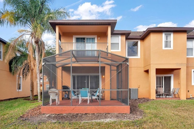 rear view of property featuring a patio, a balcony, a yard, and a lanai