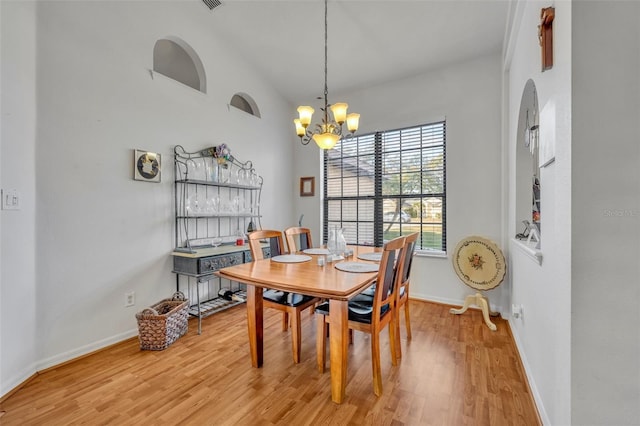 dining space with a notable chandelier, high vaulted ceiling, and wood-type flooring