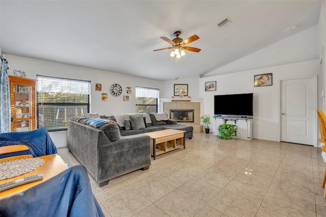 living room featuring ceiling fan, lofted ceiling, and a tiled fireplace