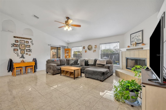 living room featuring a tiled fireplace, vaulted ceiling, and ceiling fan