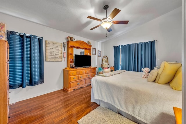 bedroom with ceiling fan, wood-type flooring, and lofted ceiling