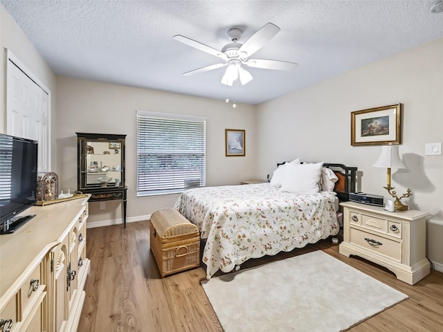 bedroom with a textured ceiling, light hardwood / wood-style floors, and ceiling fan