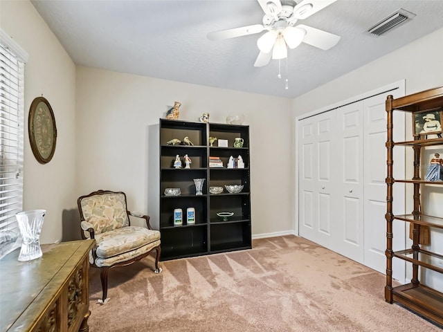 sitting room with ceiling fan and carpet flooring