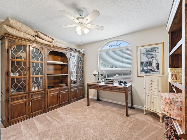 carpeted home office with ceiling fan and a textured ceiling