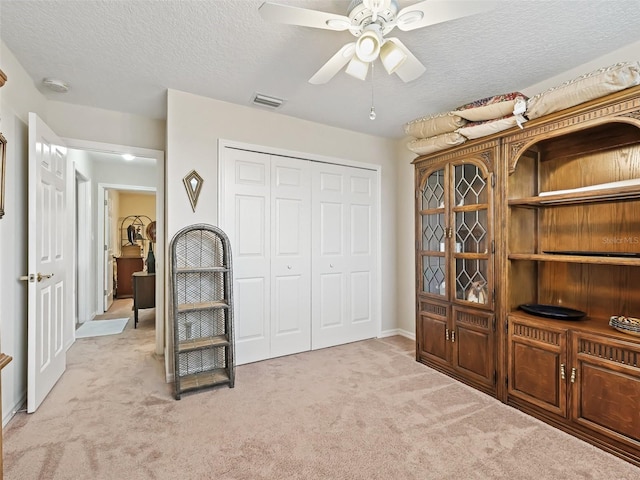 carpeted bedroom with a textured ceiling, a closet, and ceiling fan