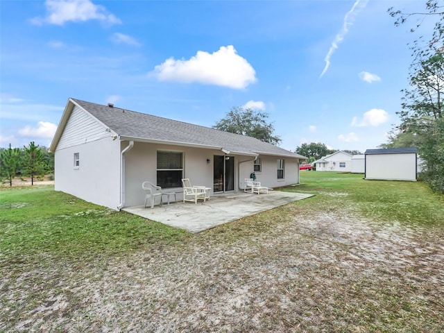 rear view of house featuring a yard, a patio area, and a storage unit