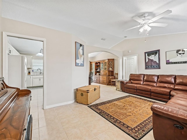 living room featuring lofted ceiling, sink, light tile patterned floors, ceiling fan, and a textured ceiling