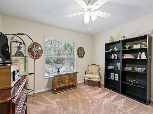 living area featuring ceiling fan, light carpet, and a textured ceiling